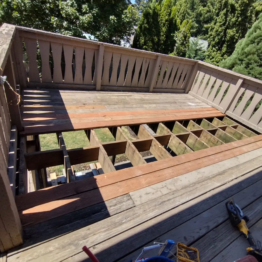 A weathered wood deck mid job, rotted boards pulled up before Curb Appeal replaced them and washed the rest