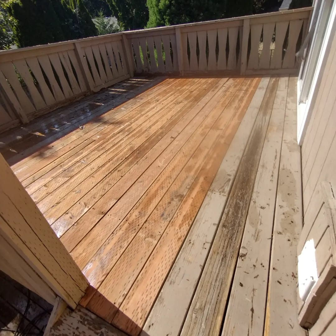 A wood deck halfway through a Curb Appeal power wash, the washed boards bright orange next to the grey unwashed boards