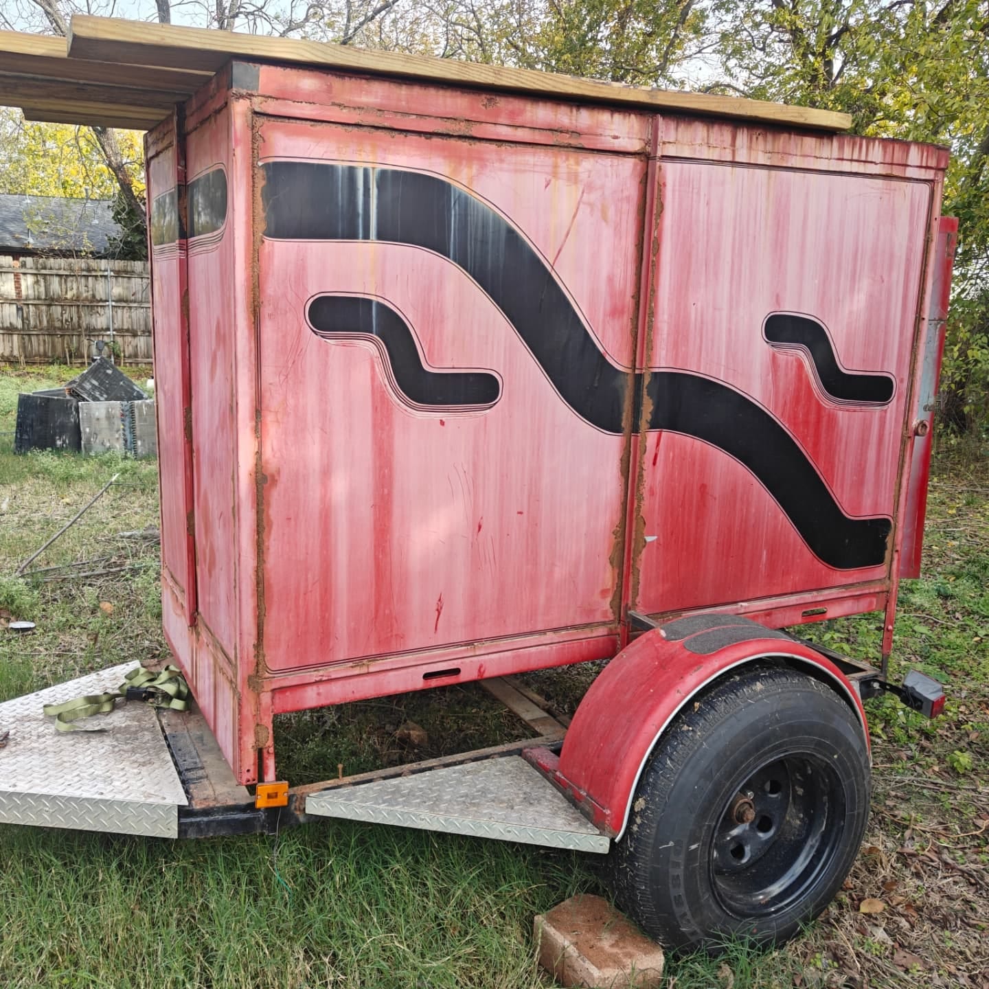 A faded red enclosed trailer with rust spots before Curb Appeal restored it